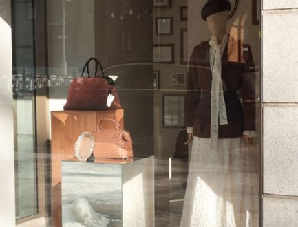 Elegant storefront display featuring a mannequin, leather handbags, and fashion accessories.