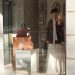 Elegant storefront display featuring a mannequin, leather handbags, and fashion accessories.